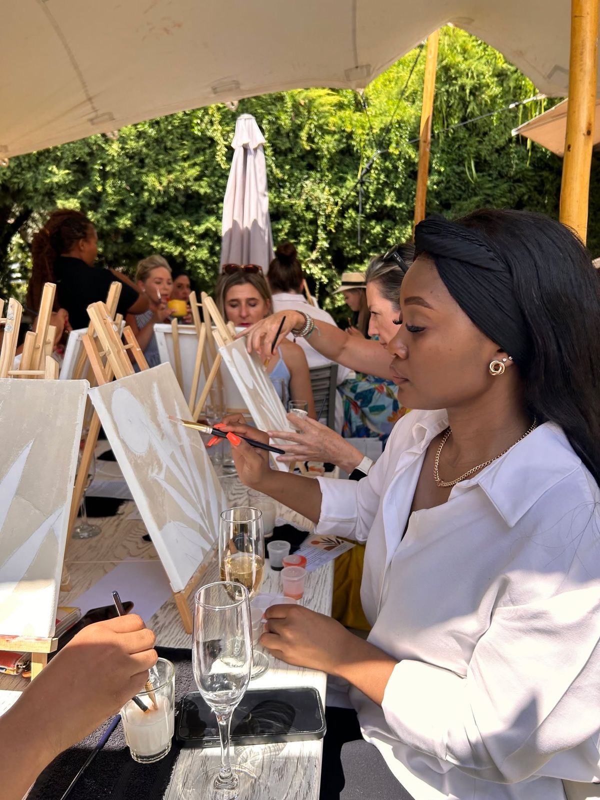 Guests painting botanical canvases at an outdoor garden paint and sip session